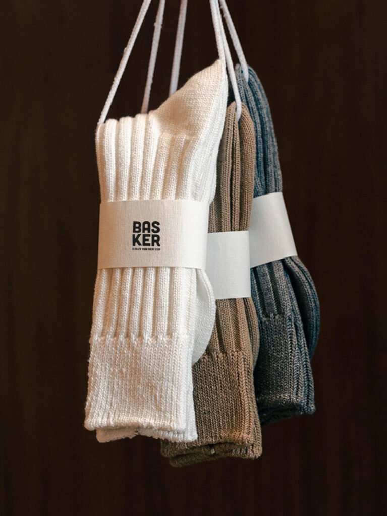 Three pairs of urban ribbed crew socks in grey, brown, and white, hanging on a line.