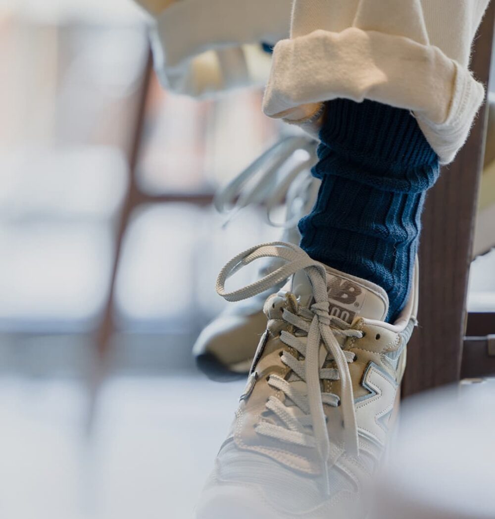 Close-up of navy urban ribbed socks paired with trainers shoes.